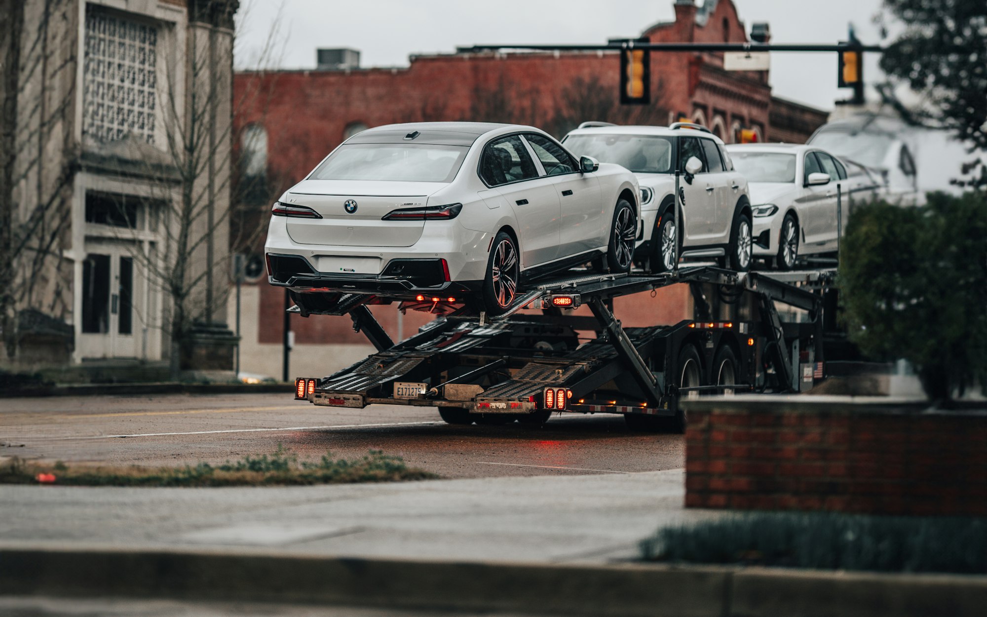 White sedans loaded on a car carrier on a town street